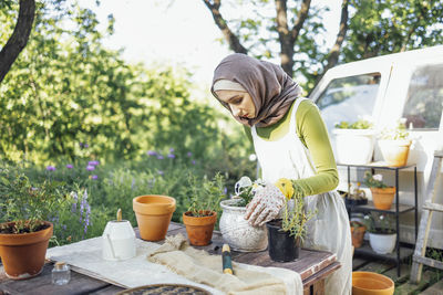 Portrait of young woman standing by plants