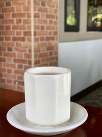 Close-up of coffee cup on table against wall