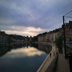 Bridge over river amidst buildings in city against sky