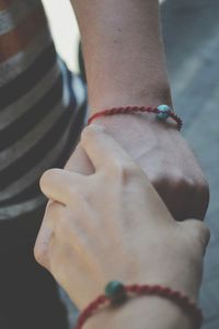 Two people with bracelets holding hands