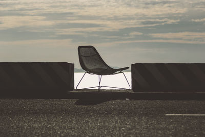 Empty chair on field against sky
