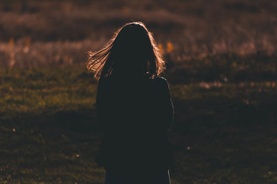 Rear view of silhouette woman standing on field