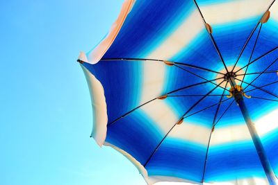 Low angle view of parasol against blue sky