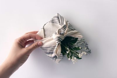 Cropped hand of woman holding gift against white background