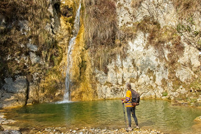 Man standing on rock by river in forest