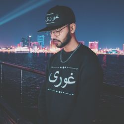 Man standing by illuminated cityscape at night