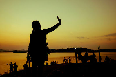 Silhouette people on beach against sky during sunset
