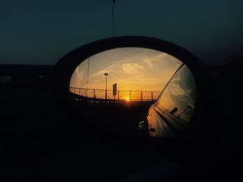 Car on side-view mirror against sky during sunset