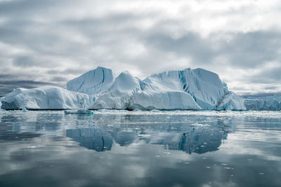 Icebergs against cloudy sky