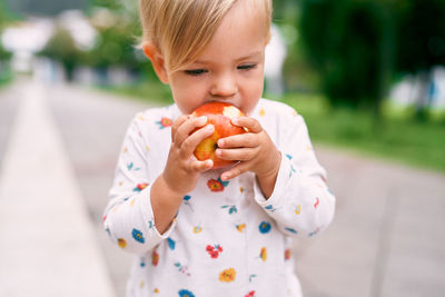 Cute girl eating apple on road