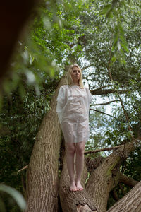 Full length of a young woman against tree trunk