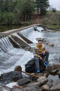 Man sitting on rock by river