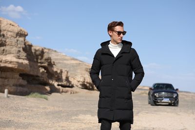 Young man wearing sunglasses standing against sky