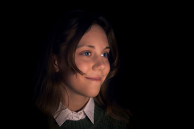 Portrait of smiling woman against black background