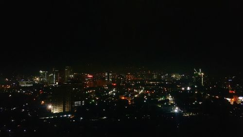 Illuminated cityscape against sky at night