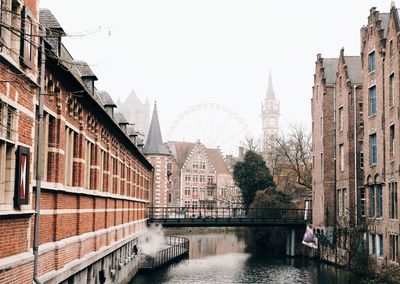 Bridge over river against buildings in city