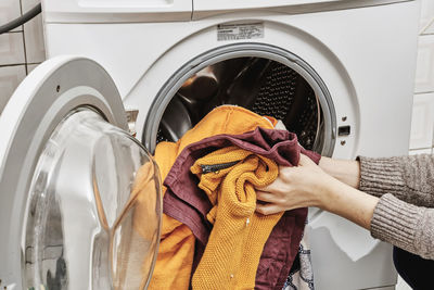 Unrecognizable woman washing dirty laundry in the washing machine