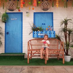 Portrait of boy sitting on bench against plants