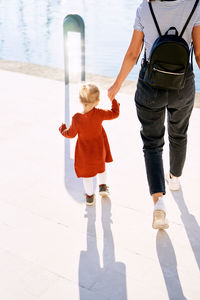 Rear view of mother and daughter on sidewalk