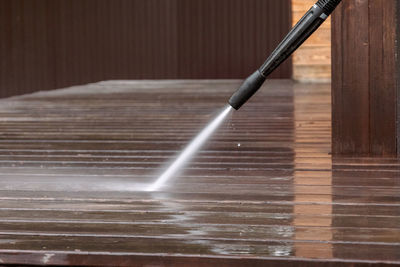 Man cleaning walls and floor with high pressure power washer. washing terrace wood planks 