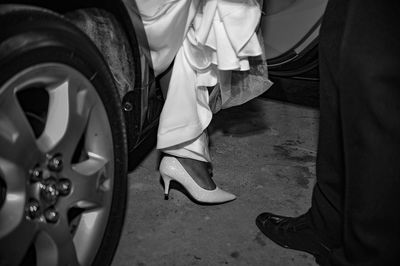 Low section of groom standing by bride disembarking from car