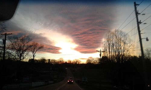 Cars on road against sky during sunset