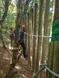 People climbing on wooden post at forest