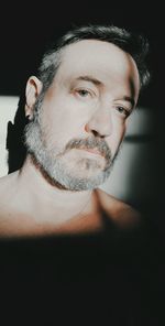 Portrait of shirtless man against black background