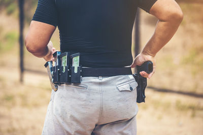 Rear view of man holding camera while standing on land