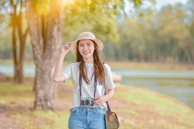 Portrait of smiling young woman standing against trees during autumn