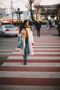 Teenage girl in warm clothing crossing road in city during winter