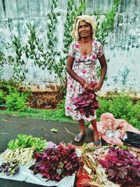 Portrait of a smiling young woman standing against plants