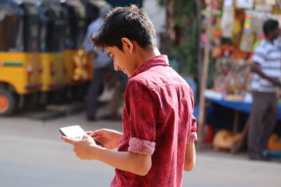 Man holding mobile phone while standing on street