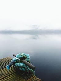 High angle view of rope tied on metal over lake against sky