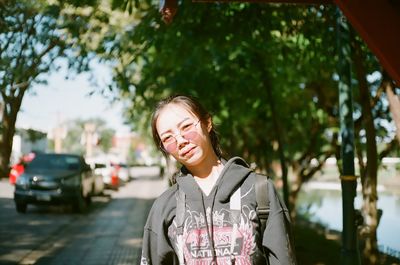 Portrait of young woman standing on footpath