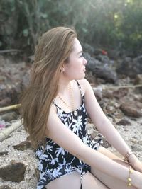 Young woman with brown hair sitting at beach