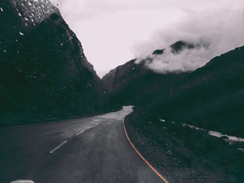 Road leading towards mountains against sky