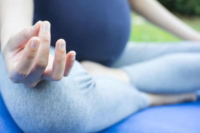 Low section of woman sitting against blue background