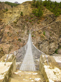 Footbridge on mountain against sky