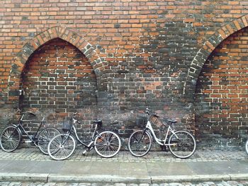 Bicycle parked against brick wall