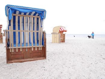 Lounge chairs on beach against clear sky