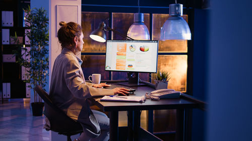 Side view of woman using digital tablet while standing at home