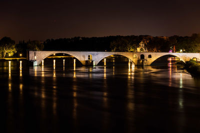 Arch bridge over river against sky at night