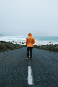 Rear view of woman standing on road