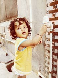 Portrait of cute girl looking away while standing against wall