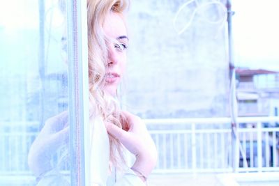 Close-up of young woman standing against window