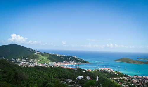 Aerial view of townscape by sea against blue sky