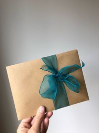 Close-up of hand holding paper against white background