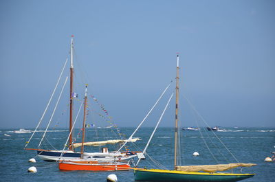 Sailboat sailing on sea against clear blue sky