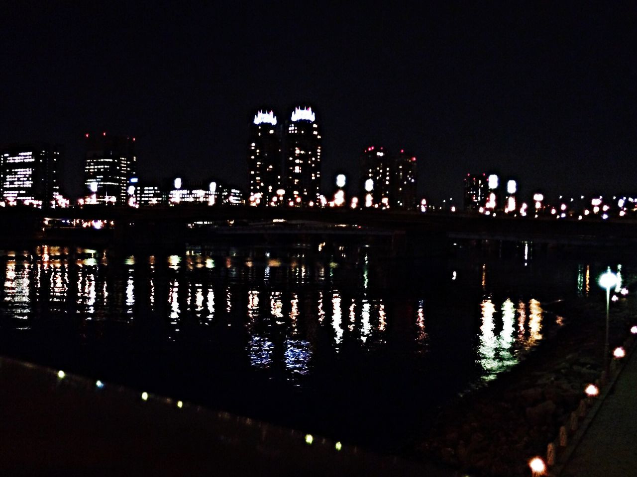 night, illuminated, architecture, built structure, reflection, water, building exterior, river, city, clear sky, waterfront, dark, sky, copy space, bridge - man made structure, lighting equipment, light - natural phenomenon, street light, outdoors, no people